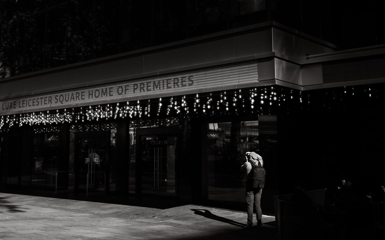 A person photographs the illuminated entrance of the Vue Leicester Square cinema at night