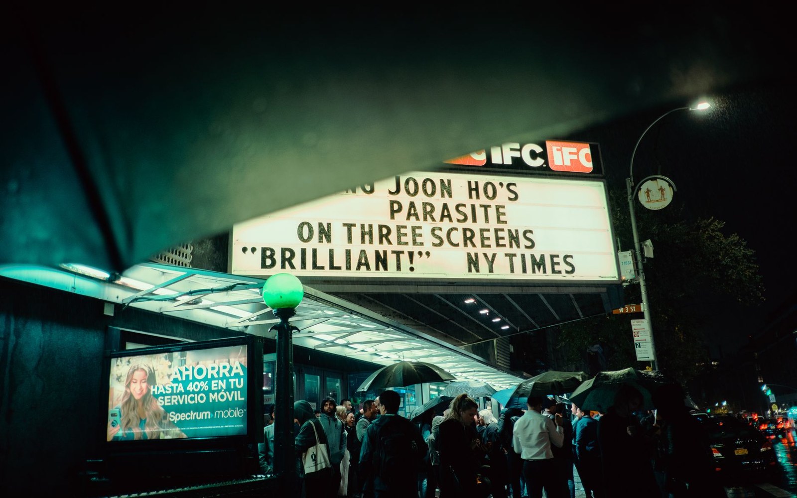 IFC theater marquee advertising Parasite as crowds gather with umbrellas on a rainy night