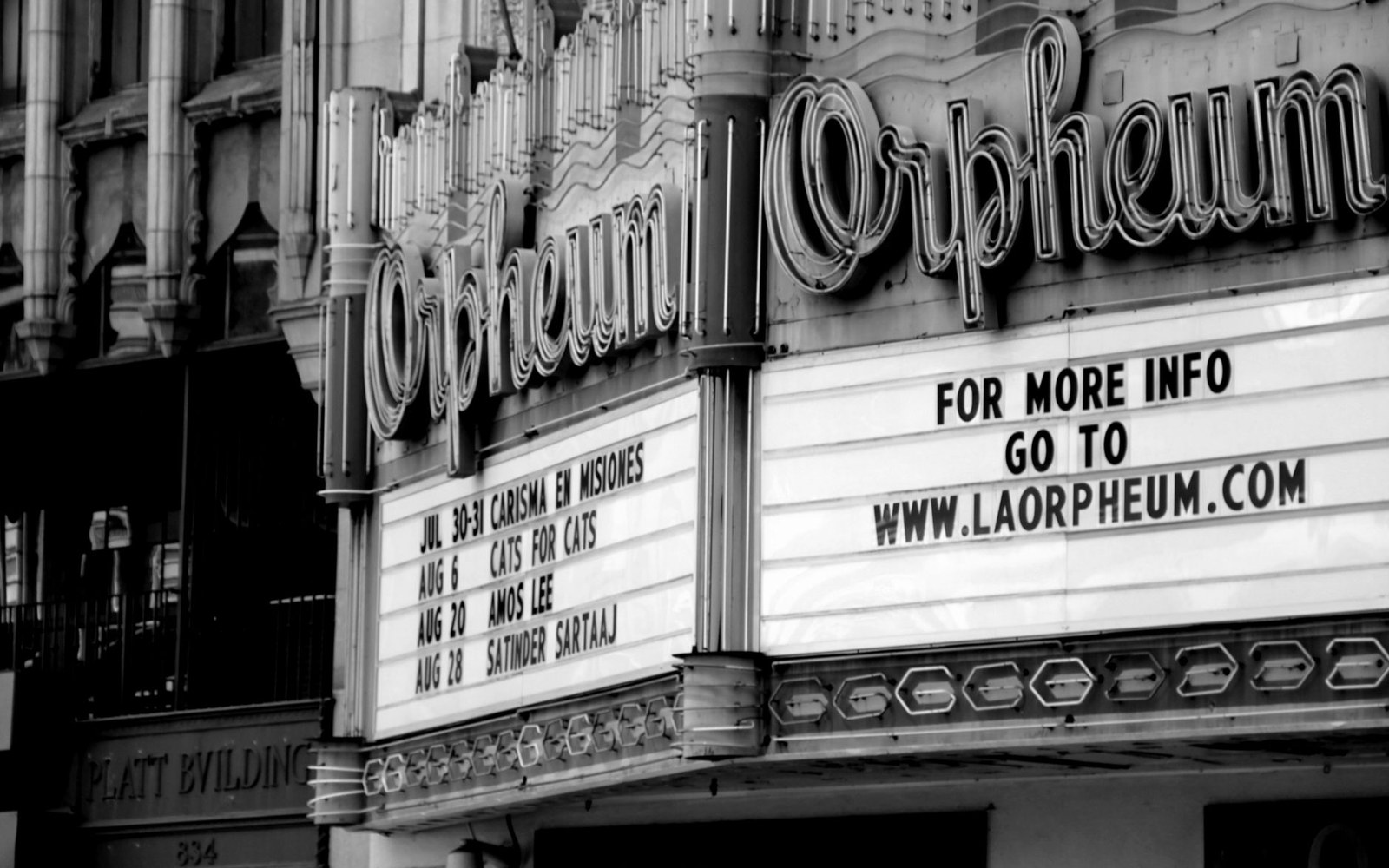 The La Paloma Theatre marquee lit at night with a film title displayed, Encinitas street visible below